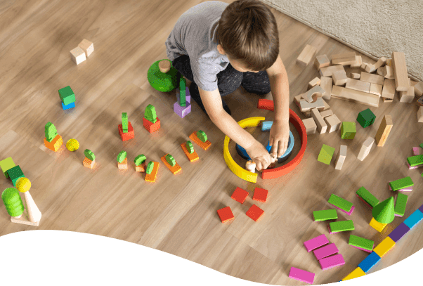 A young boy playing with blocks on the floor.