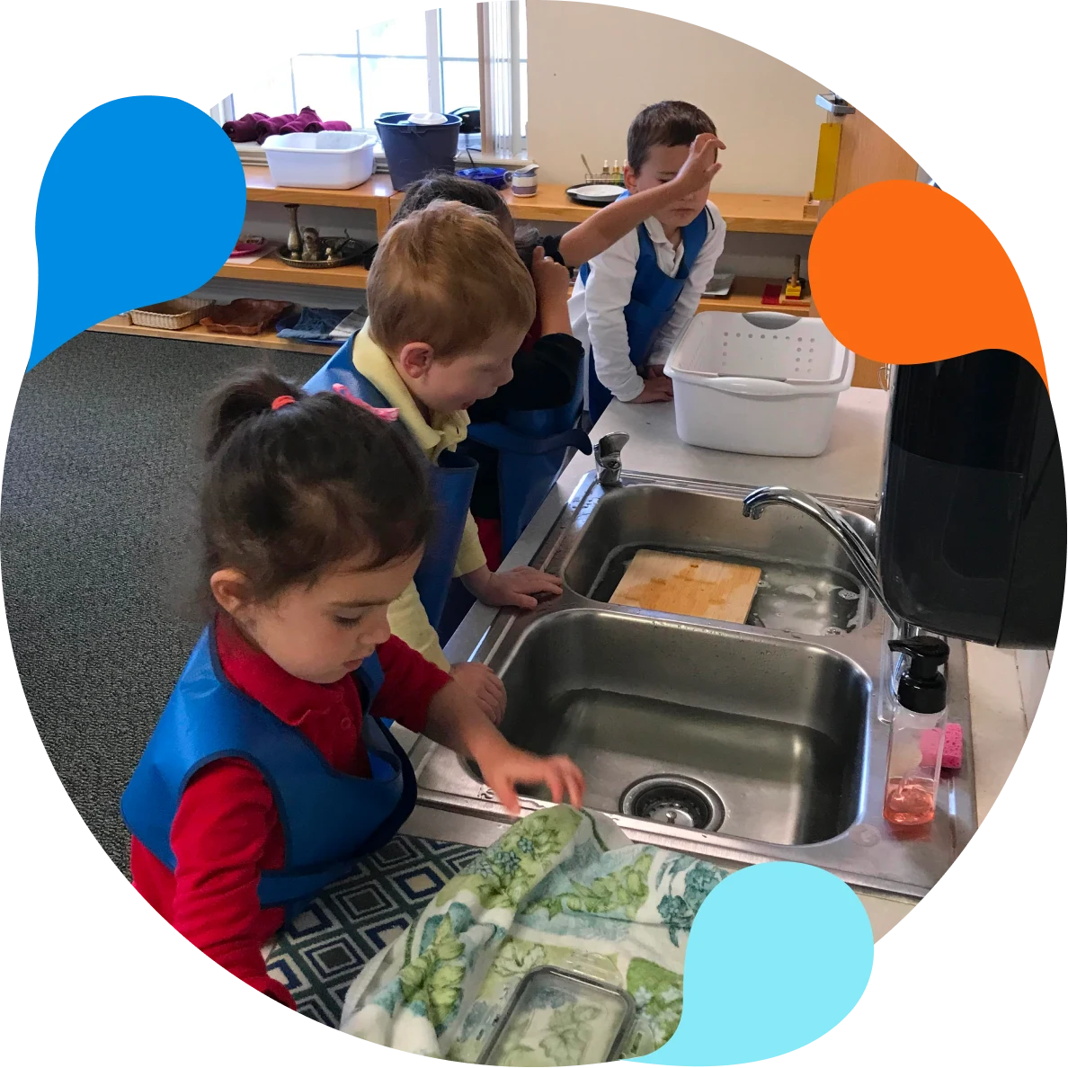 A group of children in the kitchen washing dishes.