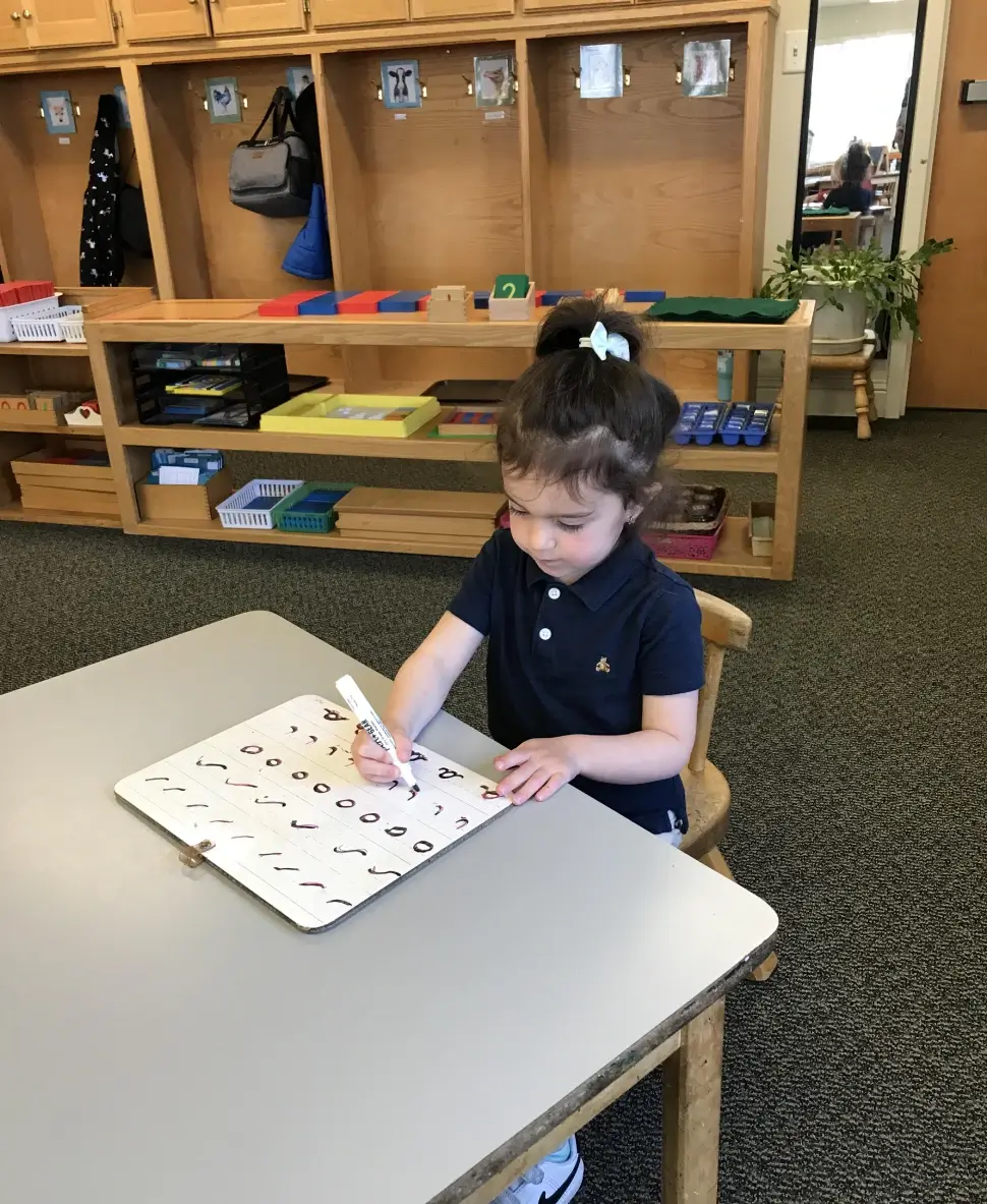 A little girl is writing on the board
