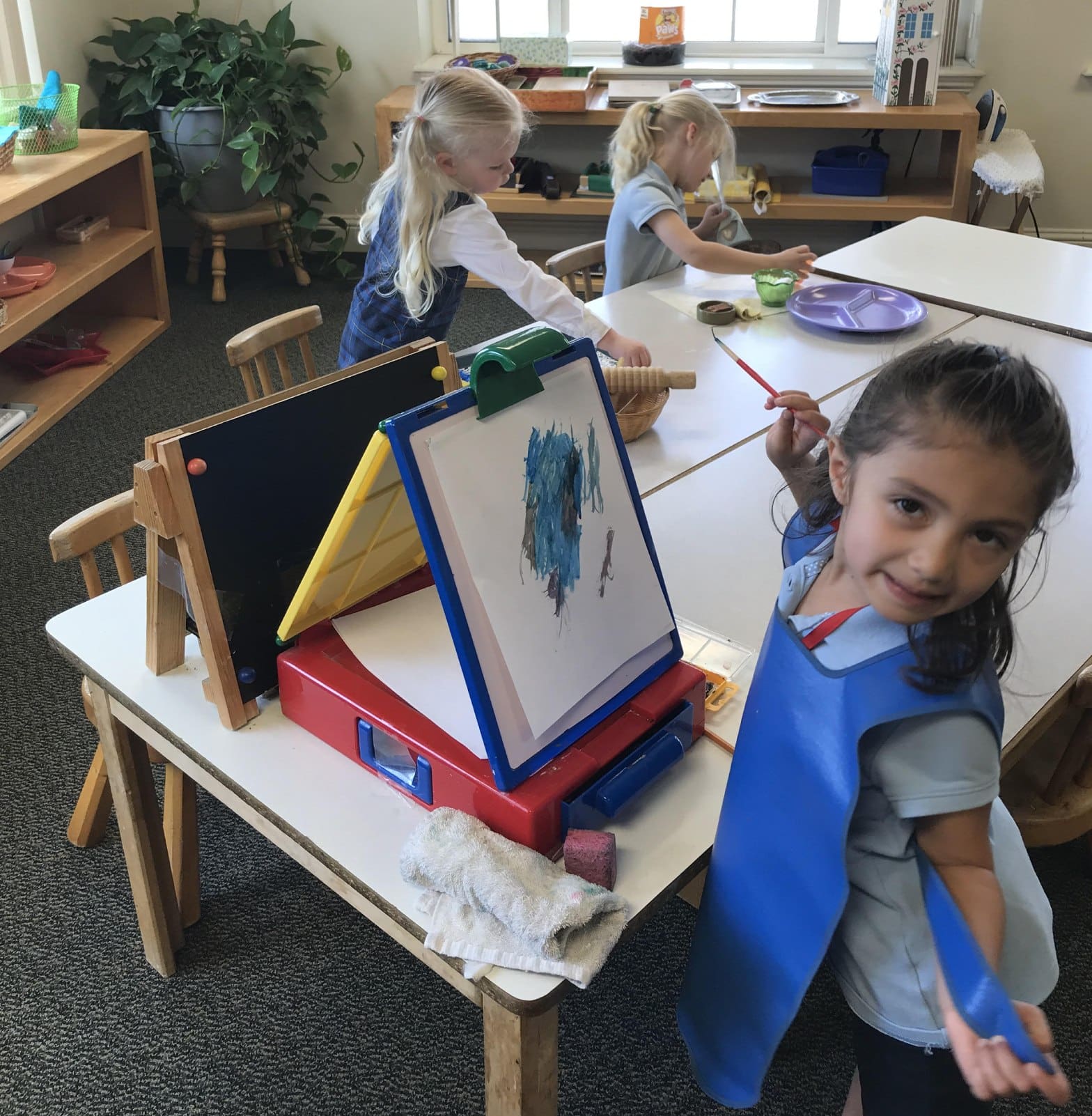 A group of children sitting at a table with art supplies.