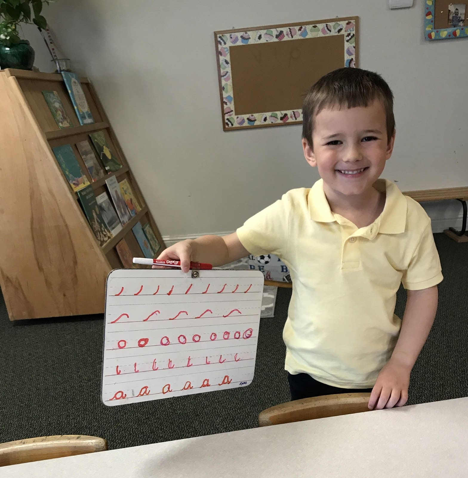 A young boy holding up an alphabet board.