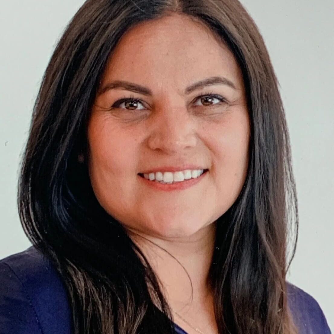 A woman with long black hair smiles for the camera.